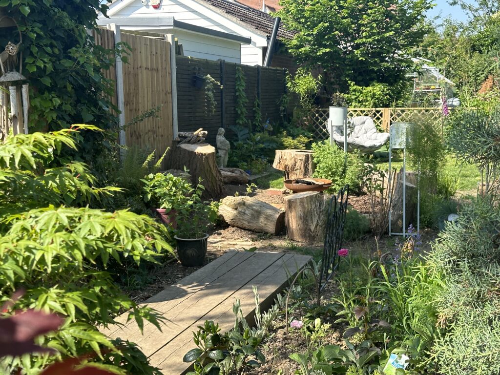 An outdoor firepit in a garden surrounded by green grass and flowers